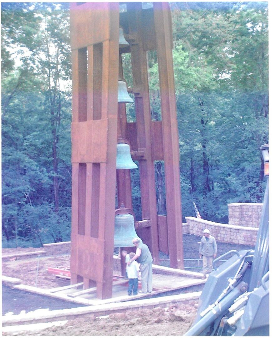People near large outdoor bell tower structure.