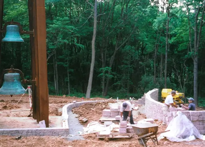 Construction site with workers and large bells.